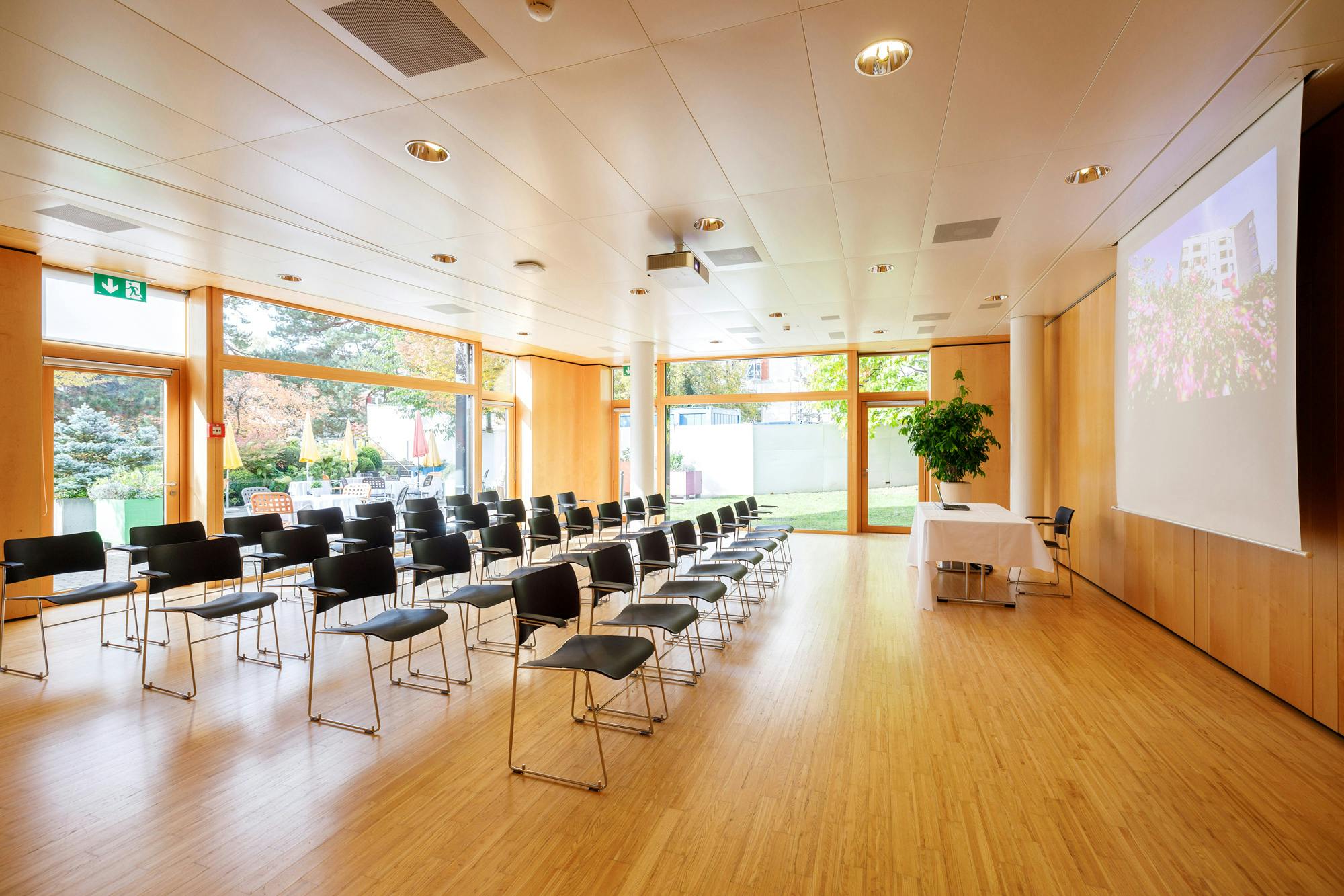 Leerer Konferenzraum mit Stuhlreihen und Holzboden.